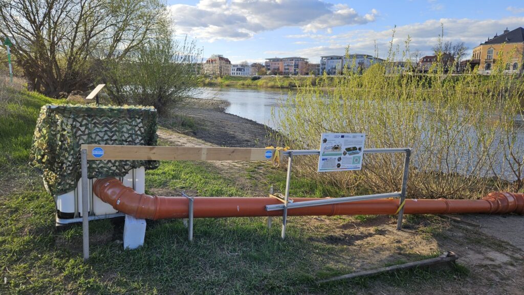 Eine orangene Rohrkonstruktion, die aussieht wie ein DIY-Bausatz aus dem Baumarkt, führt direkt in die Elbe. Daran: Sensoren, Kameras, ein Tarnnetz – und mittendrin: der Krabbenstopp.