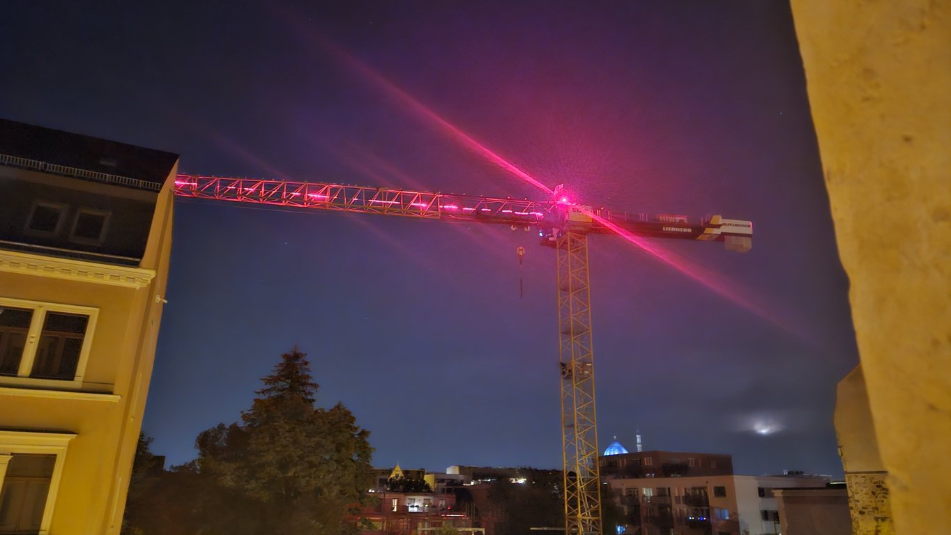 Möwen sitzen nachts auf einem rot beleuchteten Baukran an der Seminarstraße in Dresden-Friedrichstadt