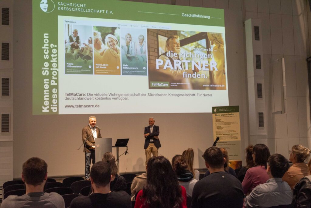 Vortrag der Sächsischen Krebsgesellschaft beim Aktionstag 2025 im Deutschen Hygiene-Museum Dresden. Besucher verfolgen eine Präsentation über das digitale Unterstützungsangebot TelMaCare.
